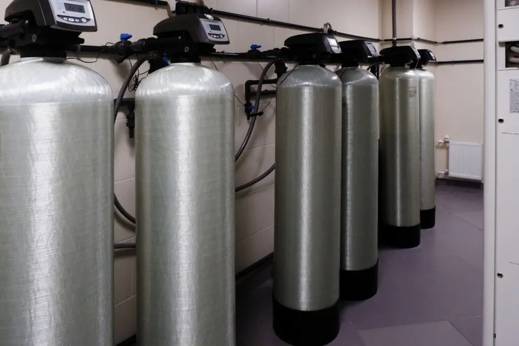 Row of commercial water softener and filtration tanks with digital control valves
