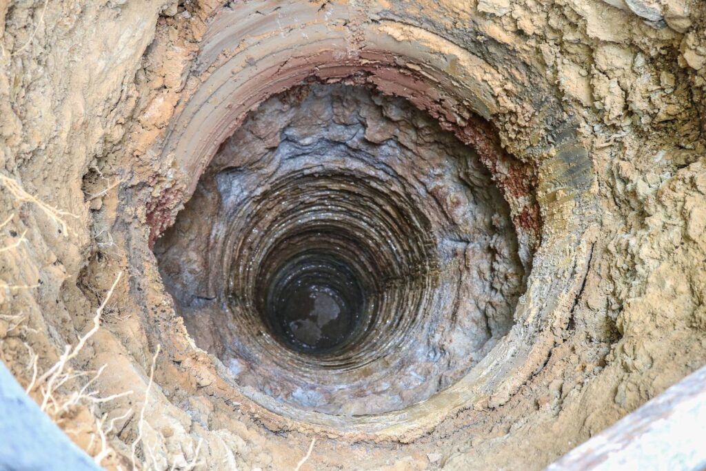 Looking down a stone-lined water well shaft to groundwater