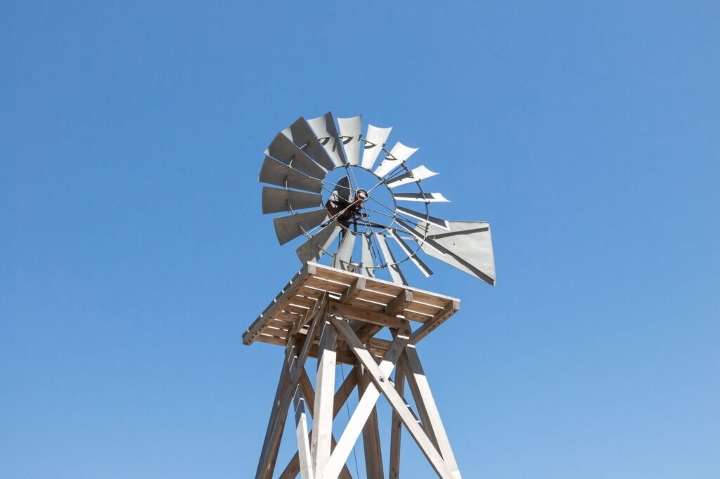 Steel farm windmill on a wooden tower against a clear blue sky